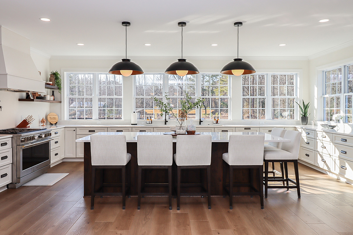 White perimeter kitchen cabinets with a dark stained island.