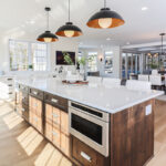 White perimeter kitchen cabinets with a dark stained island.