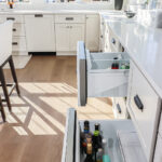 White kitchen cabinets with wine cooler drawers pulled out.