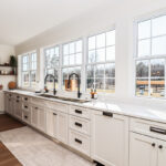 White kitchen cabinets with large row of windows above.
