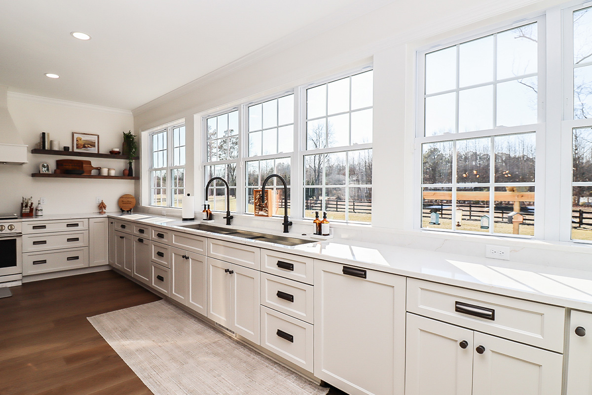 White kitchen cabinets with large row of windows above.