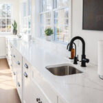 White kitchen cabinets with large row of windows above.