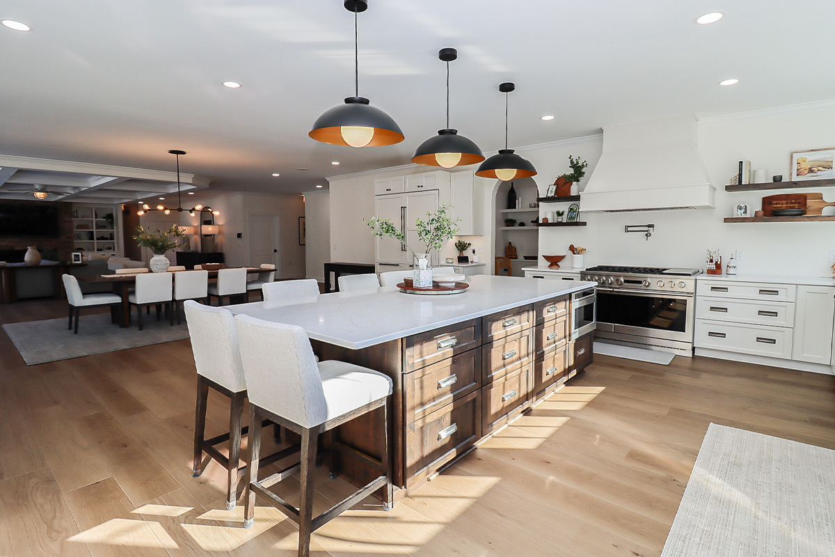 White perimeter kitchen cabinets with a dark stained island.