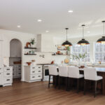 White perimeter kitchen cabinets with a dark stained island.