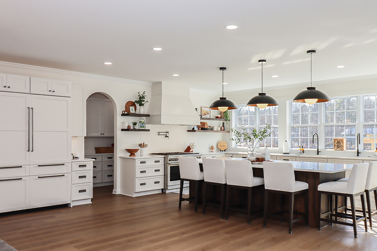White perimeter kitchen cabinets with a dark stained island.