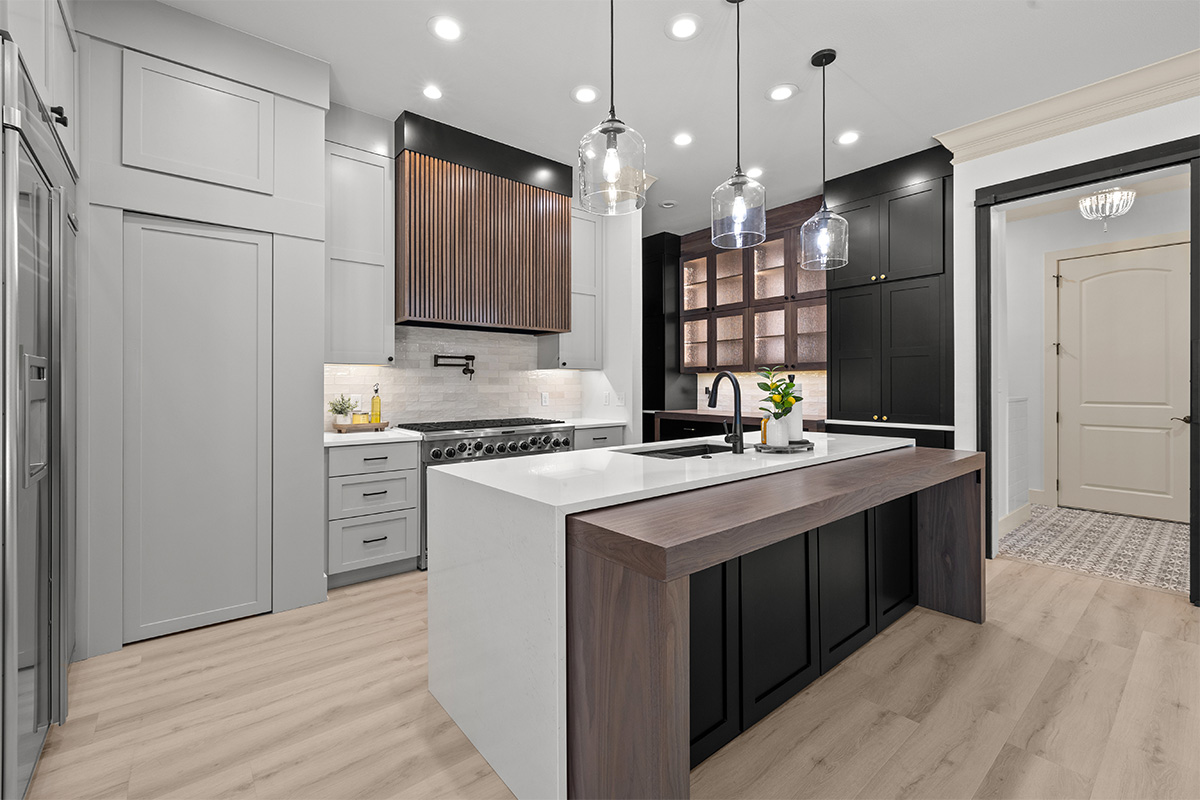 Light gray and black painted kitchen cabinets with walnut accent hutch cabinets, with a pullout walnut table connected to the island.