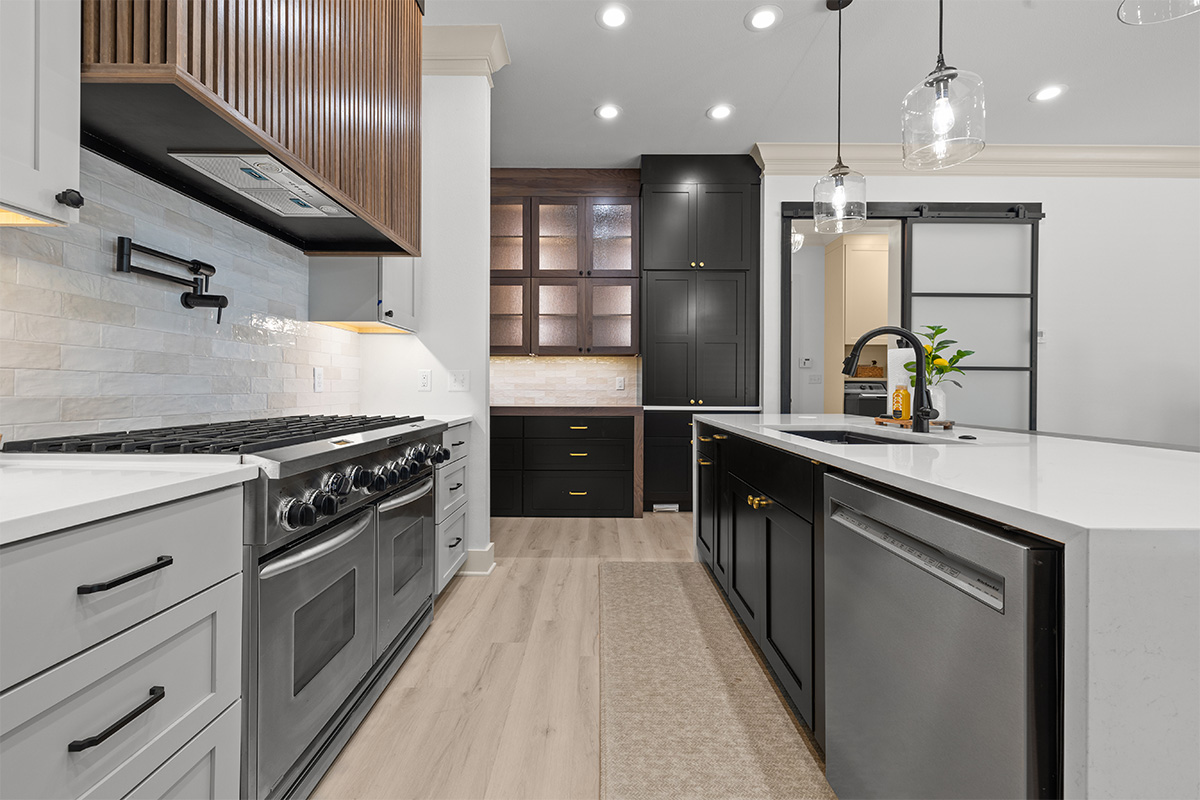 Light gray and black painted kitchen cabinets with walnut accent hutch cabinets, with a pullout walnut table connected to the island.