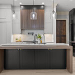 Light gray and black painted kitchen cabinets with walnut accent hutch cabinets, with a pullout walnut table connected to the island.