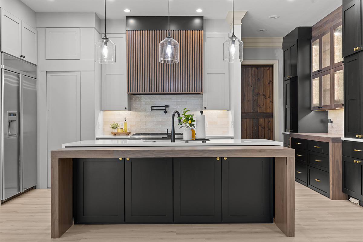 Light gray and black painted kitchen cabinets with walnut accent hutch cabinets, with a pullout walnut table connected to the island.