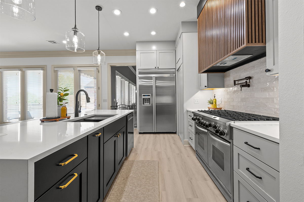 Light gray and black painted kitchen cabinets with walnut accent hutch cabinets, with a pullout walnut table connected to the island.