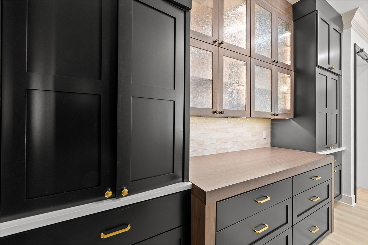 Black cabinetry surrounding a stained walnut accent hutch cabinet.
