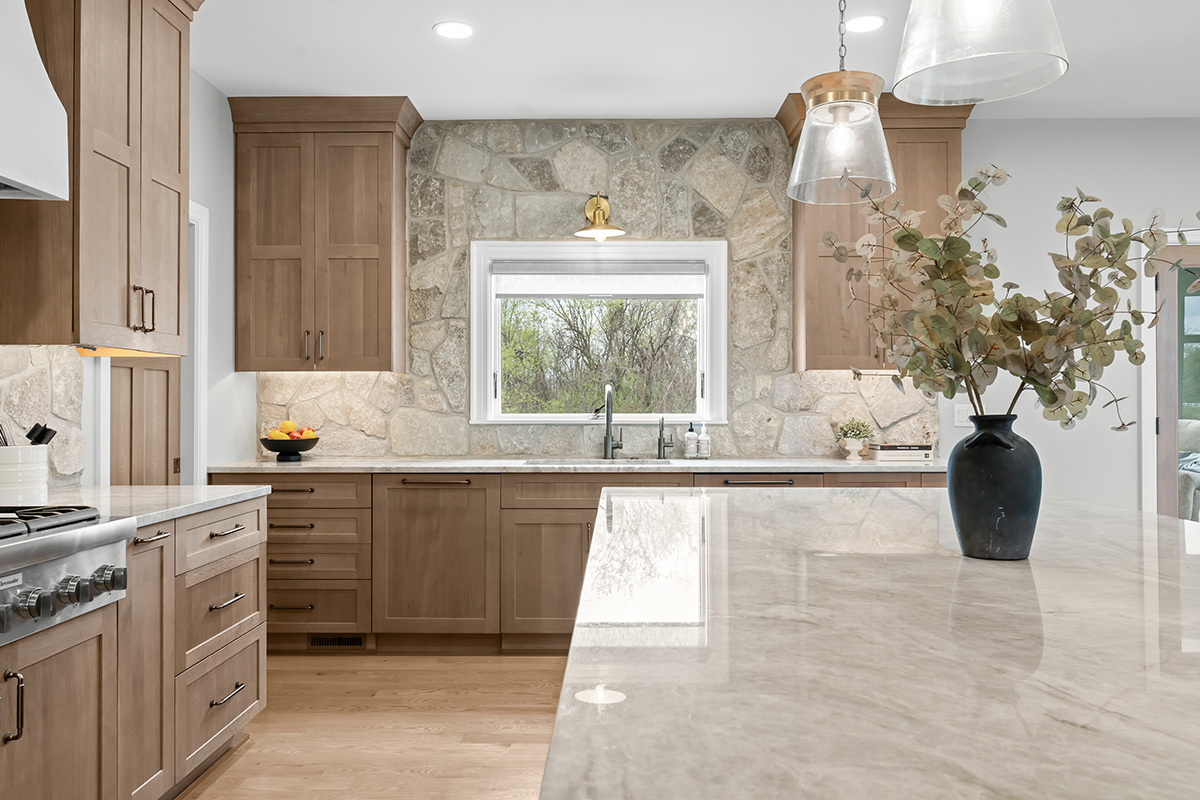 Light stained kitchen cabinets on stone wall.