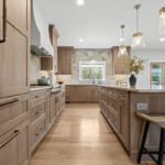 Light stained kitchen cabinets on stone wall.
