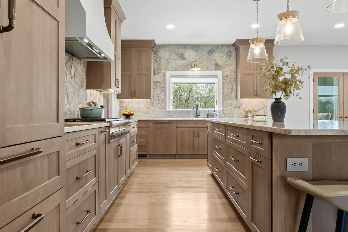 Light stained kitchen cabinets on stone wall.
