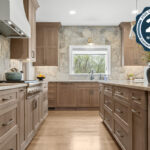 Light stained kitchen cabinets on stone wall.