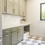 Light green mudroom cabinets with dog dish area under the counter.