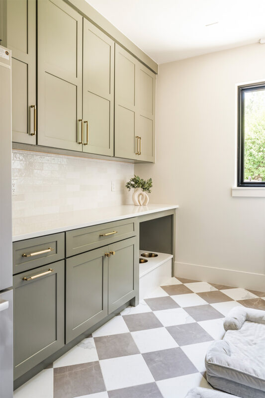 Light green mudroom cabinets with dog dish area under the counter.