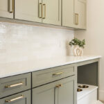 Light green mudroom cabinets with dog dish area under the counter.