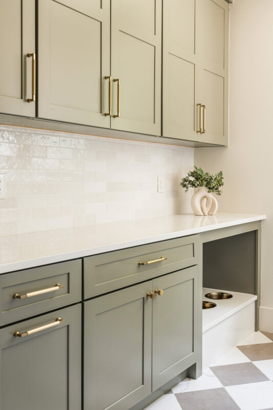 Light green mudroom cabinets with dog dish area under the counter.