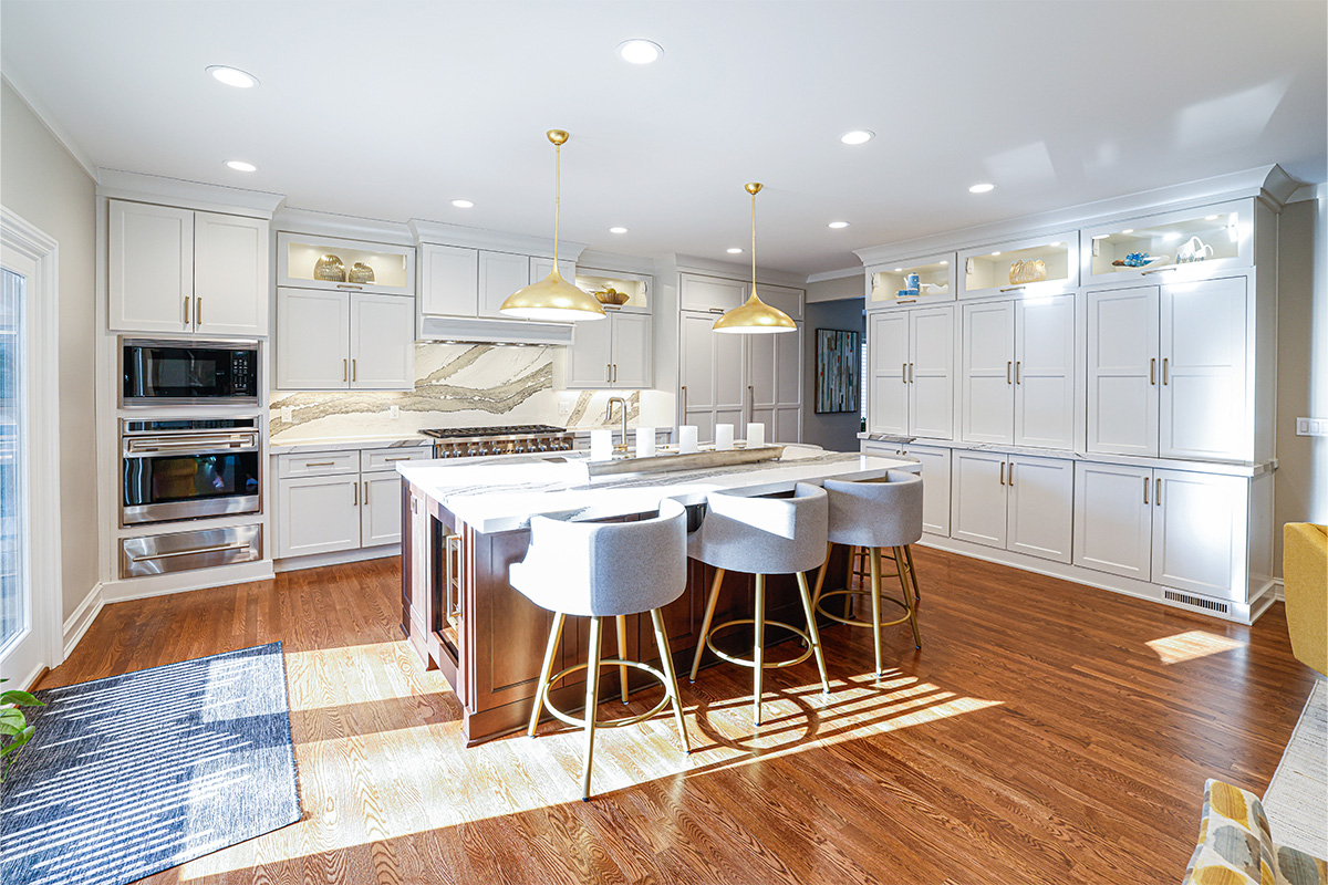 White kitchen perimeter cabinets with brown stained island and marble backsplash.