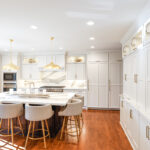 White kitchen perimeter cabinets with brown stained island and marble backsplash.