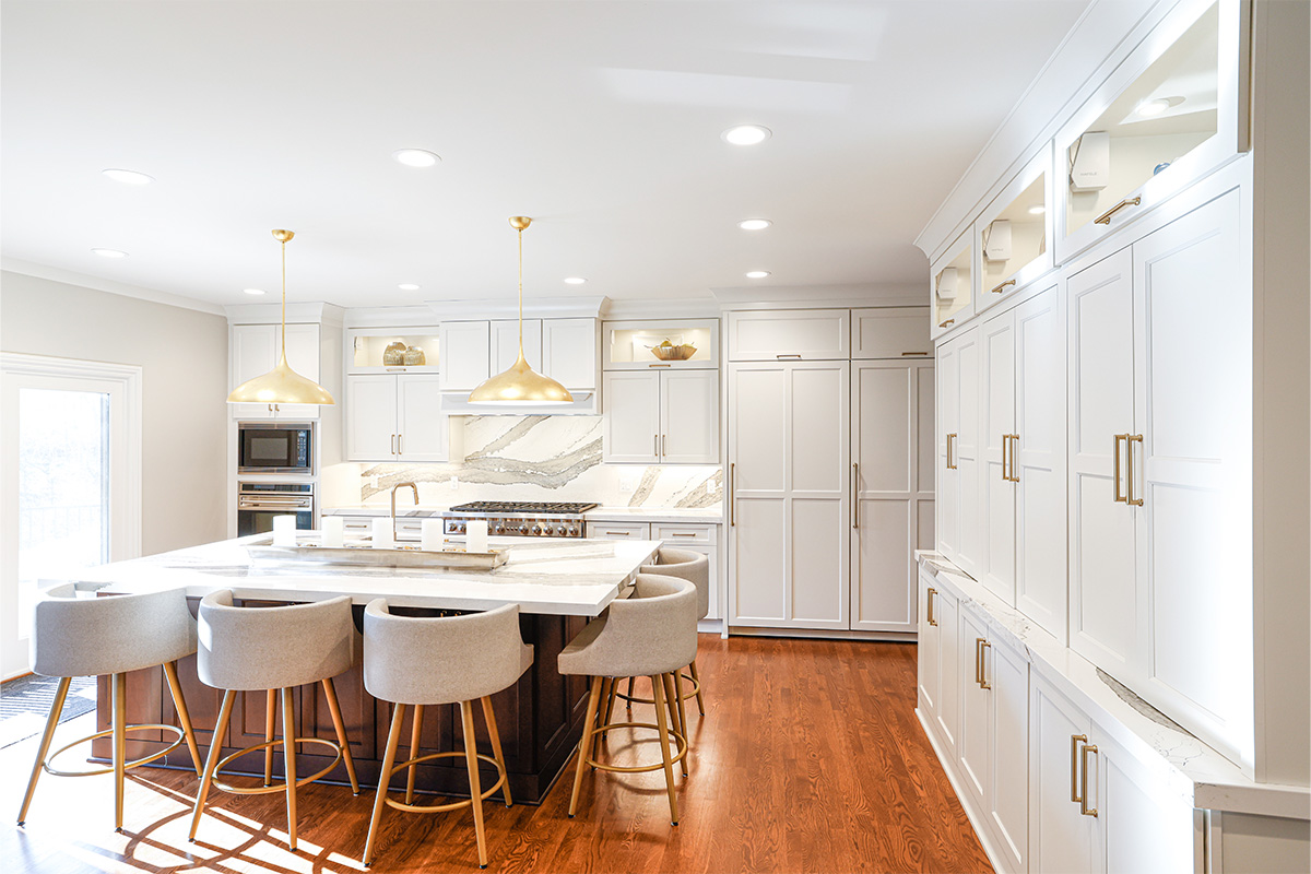 White kitchen perimeter cabinets with brown stained island and marble backsplash.