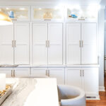 Tall white kitchen cabinets with glass top doors.