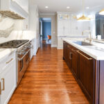 White kitchen perimeter cabinets with brown stained island and marble backsplash.