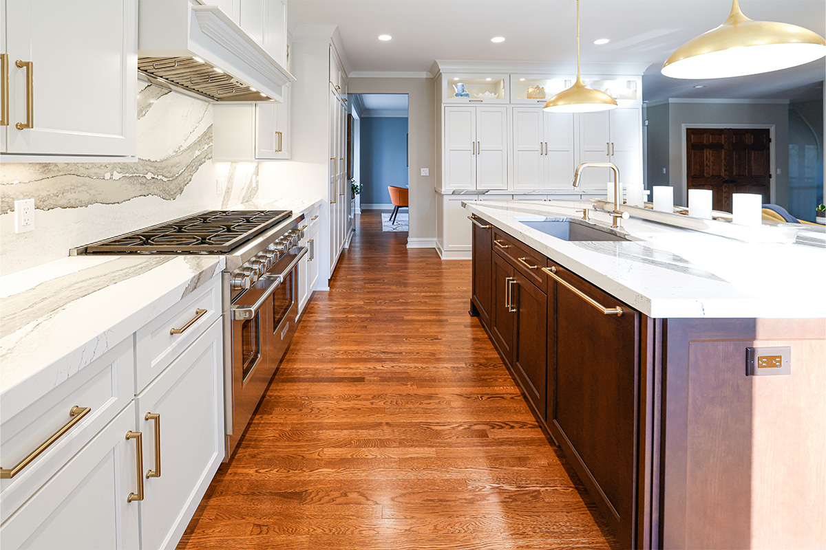 White kitchen perimeter cabinets with brown stained island and marble backsplash.