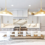 White kitchen perimeter cabinets with brown stained island and marble backsplash.