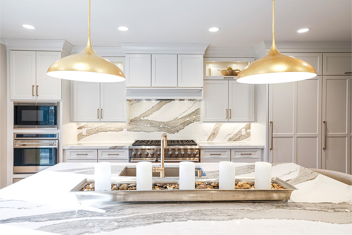 White kitchen perimeter cabinets with brown stained island and marble backsplash.