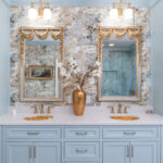 Light blue bathroom vanity cabinets with ornate gold mirrors and sink hardware.