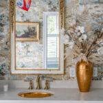 Light blue bathroom vanity cabinets with ornate gold mirrors and sink hardware.