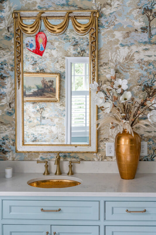Light blue bathroom vanity cabinets with ornate gold mirrors and sink hardware.