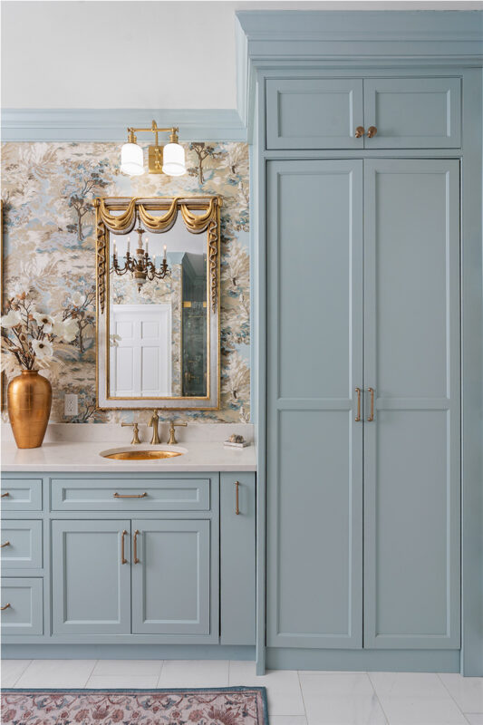 Light blue bathroom vanity cabinets with ornate gold mirrors and sink hardware.