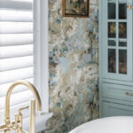 Light blue bathroom cabinet with flowered wall paper.