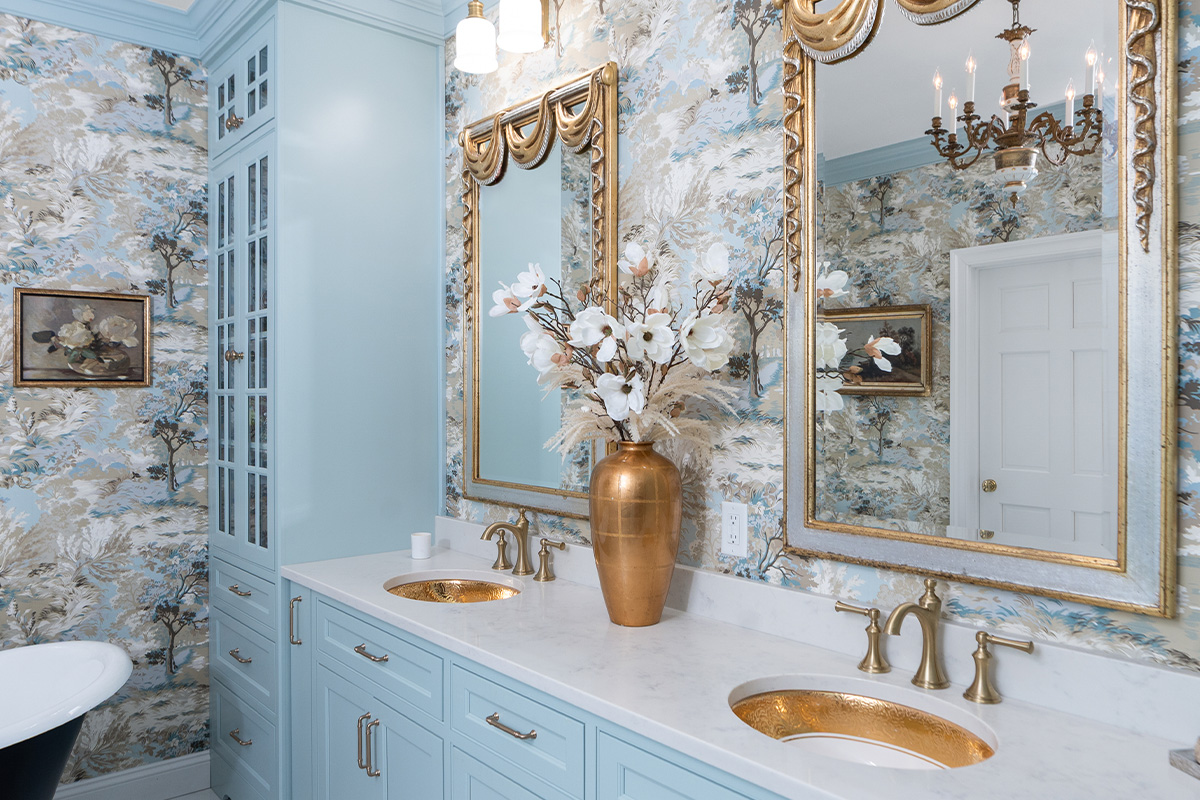 Light blue bathroom vanity cabinets with ornate gold mirrors and sink hardware.