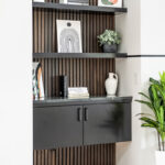 Black painted floating cabinet with floating shelves above.
