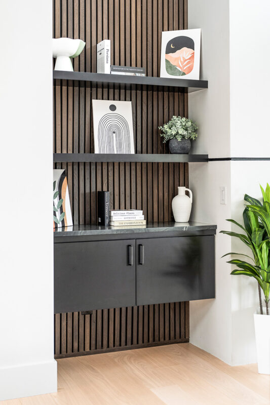 Black painted floating cabinet with floating shelves above.