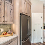 Light stain on perimeter kitchen cabinets with fridge.