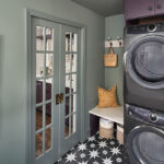 Purple stacked washer and dryer with stained wood floating shelves.
