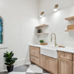 Light stained mudroom cabinets with farmer sink and floating shelves.