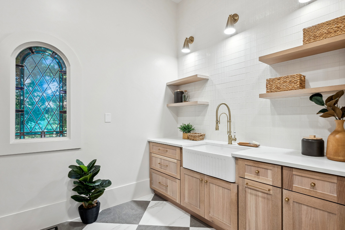 Light stained mudroom cabinets with farmer sink and floating shelves.