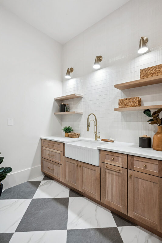 Light stained mudroom cabinets with farmer sink and floating shelves.