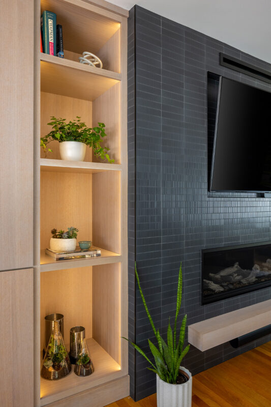 Dark brick fireplace with TV above and light stained cabinets on both sides.