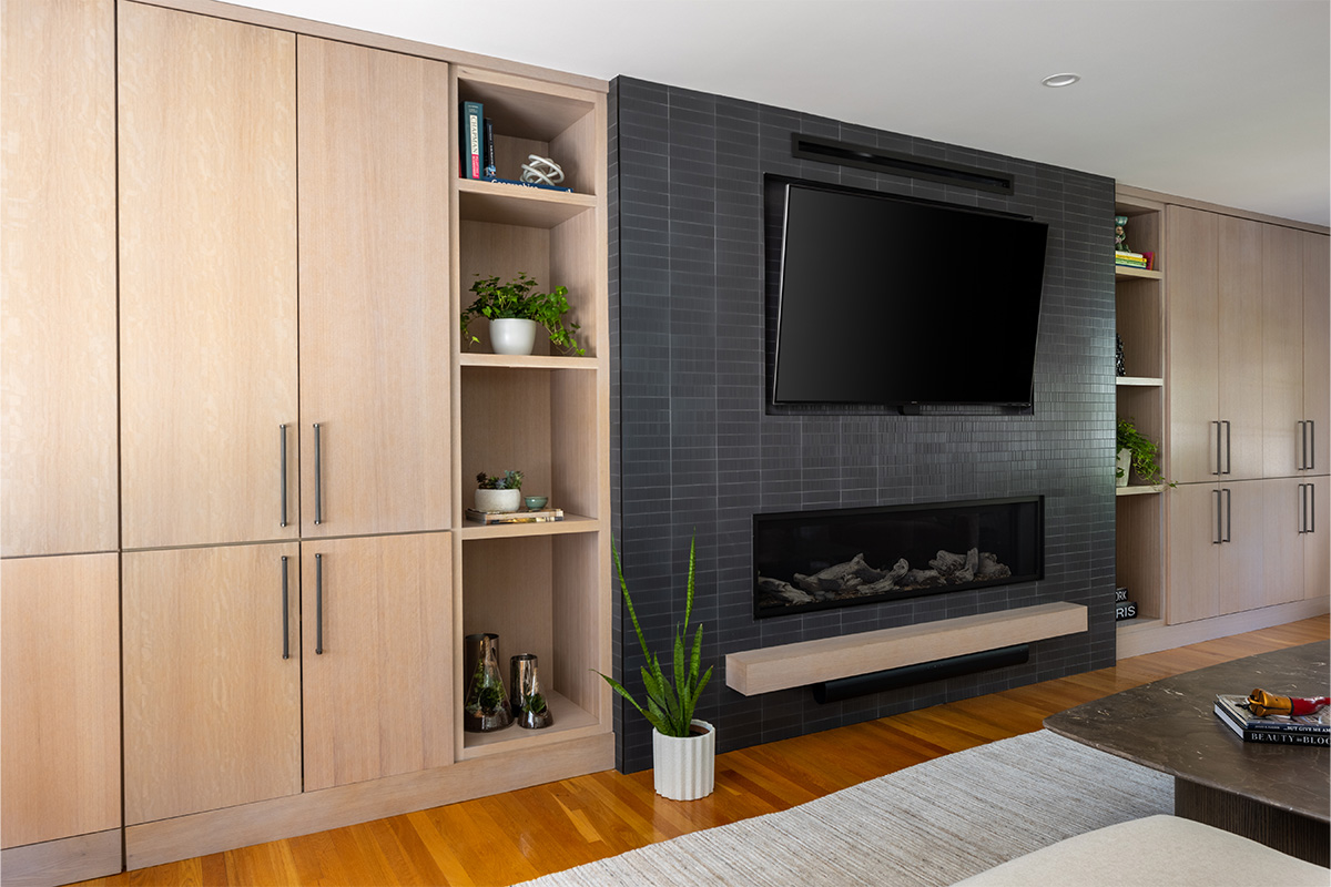 Dark brick fireplace with TV above and light stained cabinets on both sides.