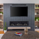 Dark brick fireplace with TV above and light stained cabinets on both sides.
