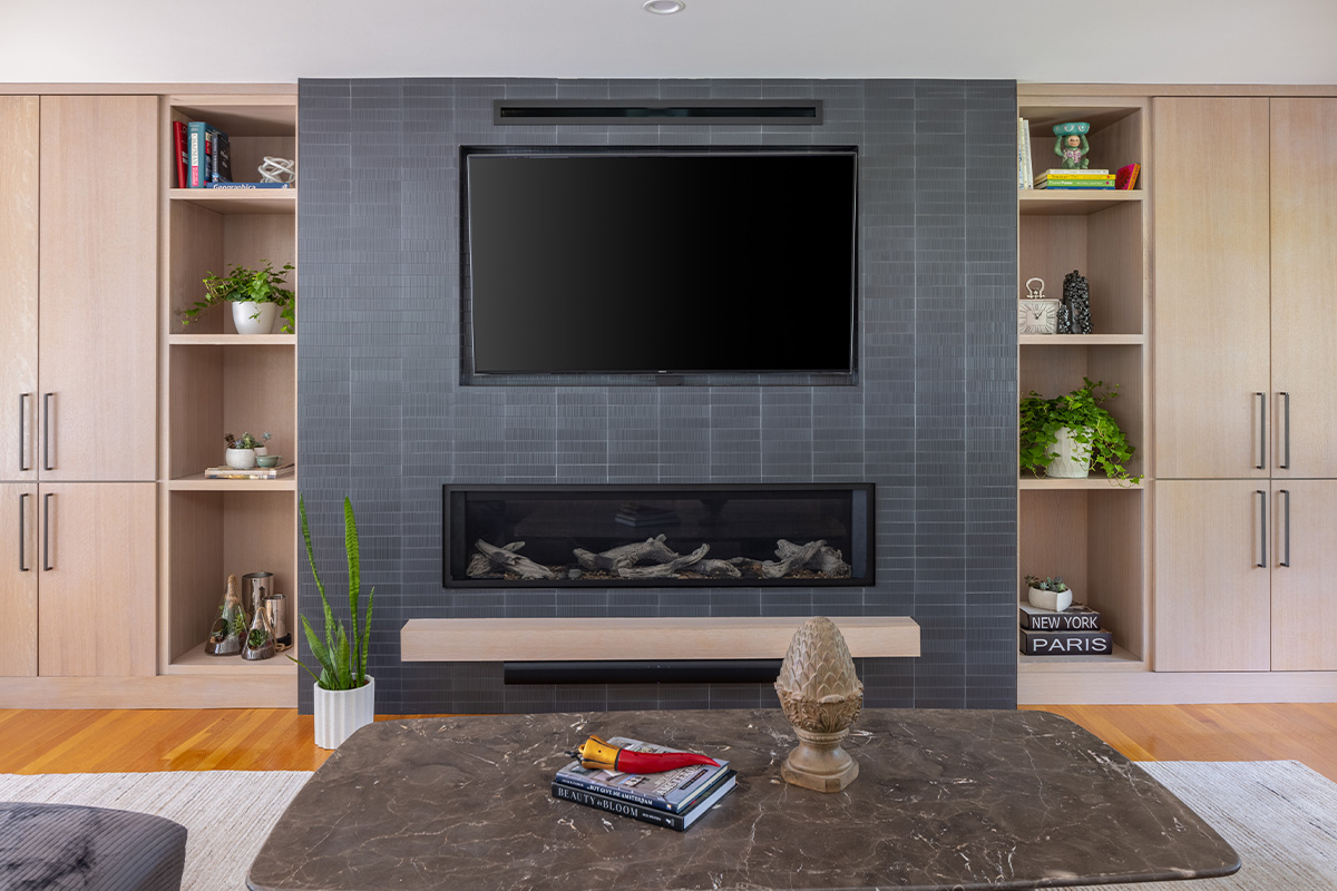 Dark brick fireplace with TV above and light stained cabinets on both sides.