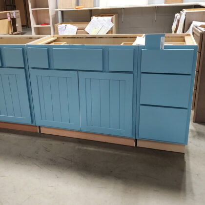 Blue painted vanity cabinets and drawer base in a warehouse setting.