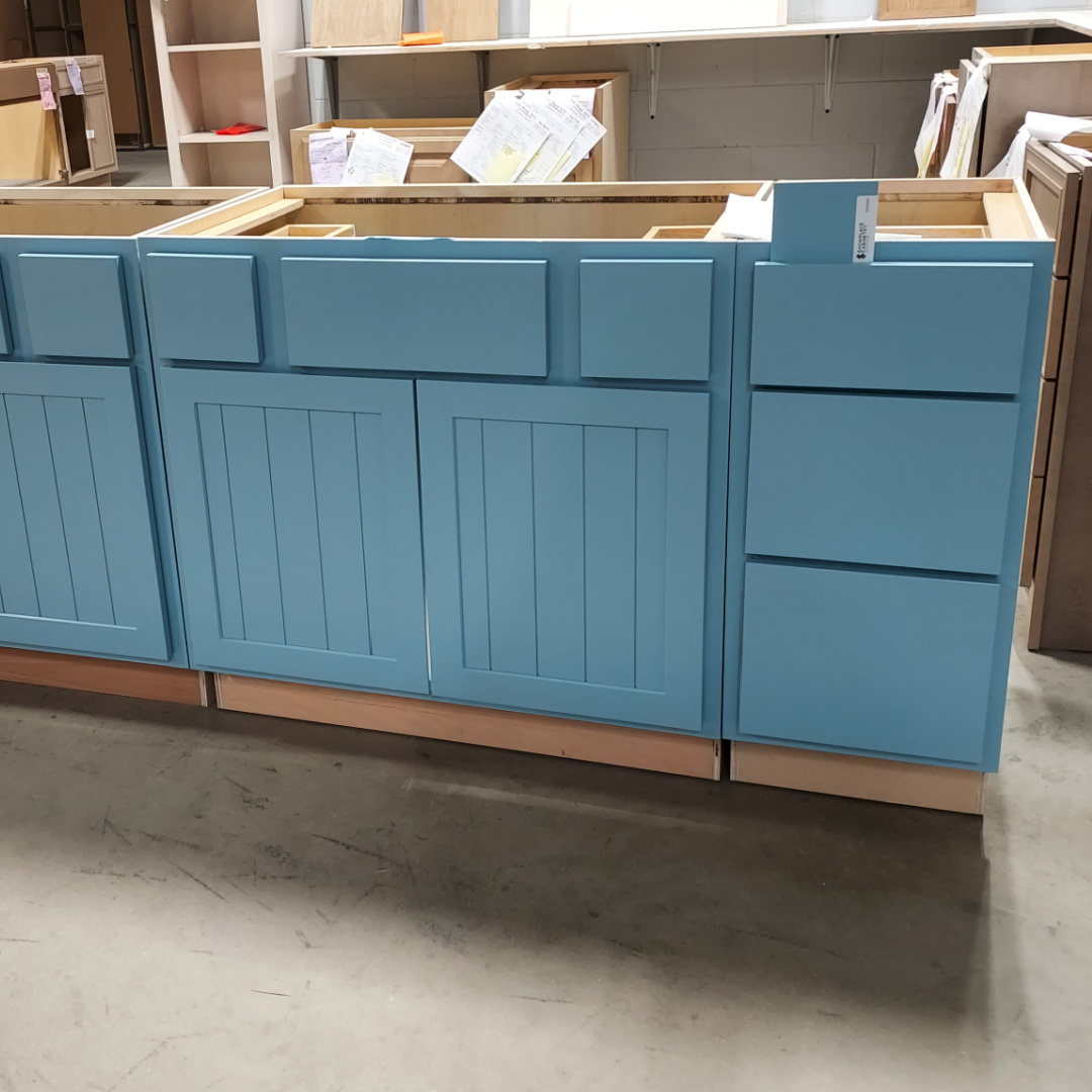 Blue painted vanity cabinets and drawer base in a warehouse setting.